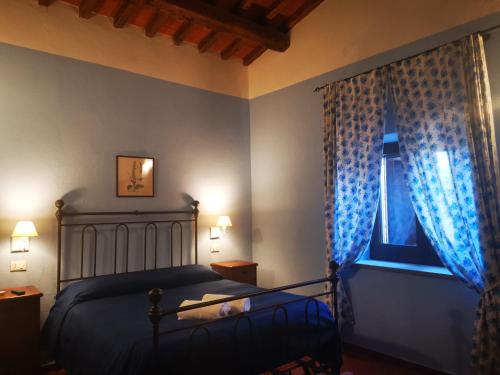 a bedroom with a bed and a window with blue curtains at Agriturismo Podere S. Croce in Saturnia