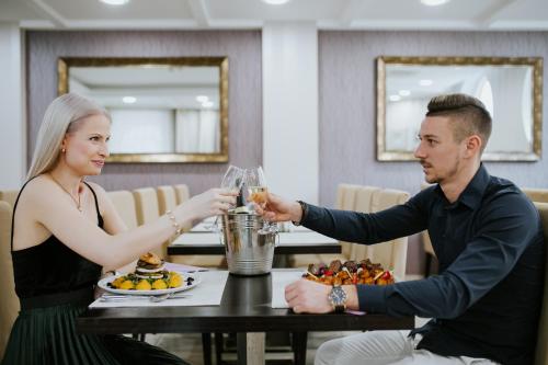 a man and a woman sitting at a table with glasses at Elixír Medical Wellness Hotel in Mórahalom