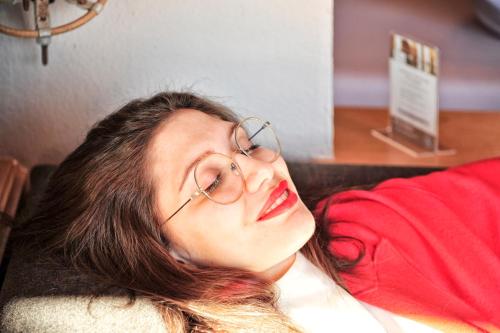 a woman with glasses laying on a couch at Die Seefelderin - Boutiquehotel St. Georg in Seefeld in Tirol