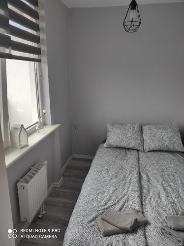 Habitación blanca con cama y ventana en Nadmorski Apartament, en Gdansk