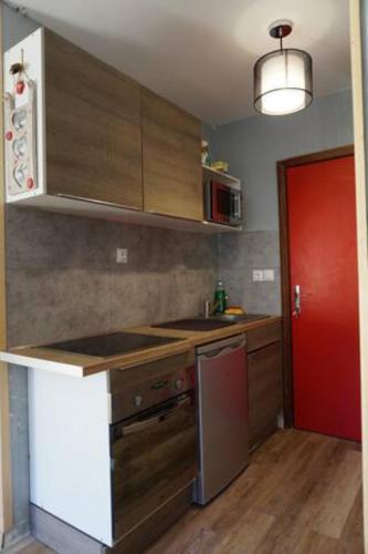 une cuisine avec des placards en bois et une porte rouge dans l'établissement Studio au pied des pistes à la Bresse Hohneck, à La Bresse