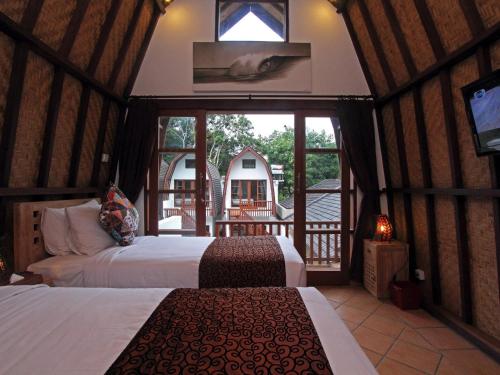 a bedroom with two beds and a balcony with a tv at Mojo Resort Canggu in Canggu