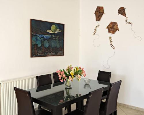 a dining room table with chairs and a vase with flowers at Seafront Home Villa in Kato Gouves