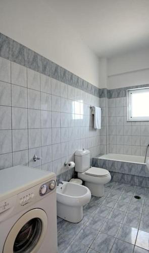 a bathroom with a toilet and a washing machine at Seafront Home Villa in Kato Gouves