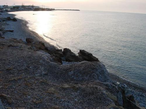 a group of rocks on a beach near the water at Seafront Home Villa in Kato Gouves