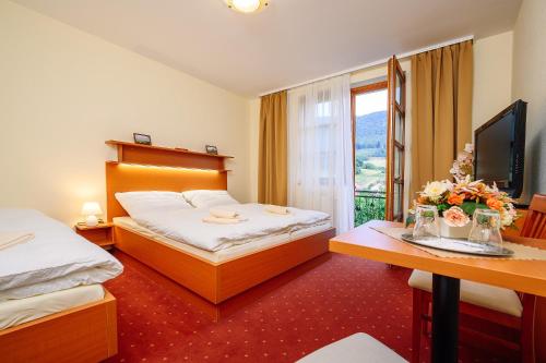 um quarto de hotel com duas camas e uma secretária e uma janela em Penzión Pod Babou em Omšenie
