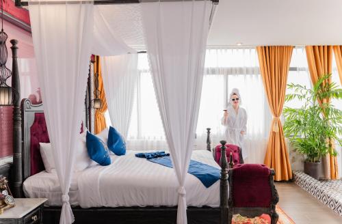 a woman standing in a bedroom with a bed at Athena Hotel Quy Nhơn in Quy Nhon