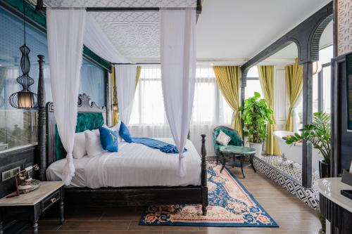 a bedroom with a canopy bed with blue walls at Athena Hotel Quy Nhơn in Quy Nhon