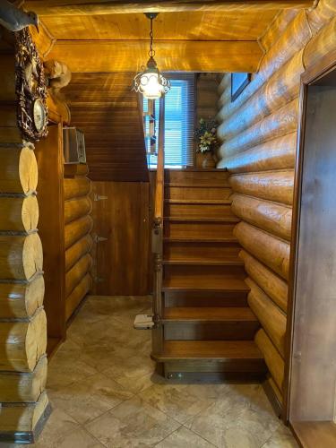 a spiral staircase in a log cabin with a light at У Фёдера и Маргариты in Nizhnyaya Grabovnitsa