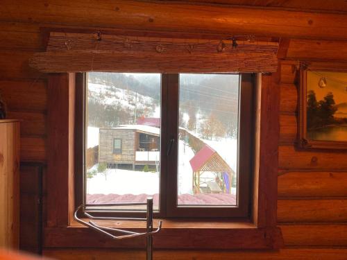 a window in a cabin with a view of a snow covered mountain at У Фёдера и Маргариты in Nizhnyaya Grabovnitsa