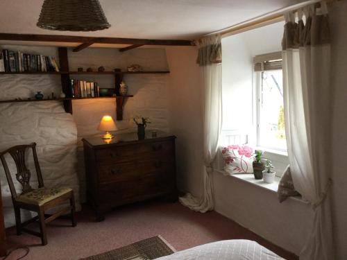 ein Schlafzimmer mit einem Bett, einer Kommode und einem Fenster in der Unterkunft Jasmine Cottage in Lerryn