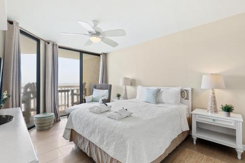 a white bedroom with a bed and a balcony at 115 Charleston Oceanfront Villas Beach Daze in Folly Beach
