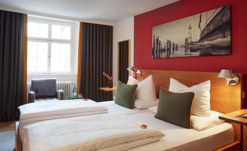 Hotel Engel - Lindauer Bier und Weinstube في لينداو: سريرين في غرفة الفندق بجدران حمراء