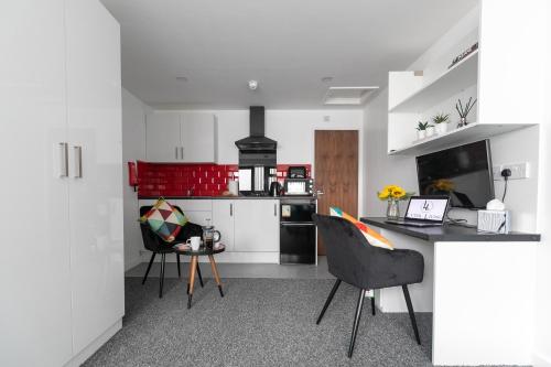 a kitchen with white cabinets and a table and chairs at Studio Apartments by Lyter Living Desks & Wifi - Monthly Stays Available in Leicester