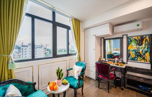 a living room with a table and chairs and windows at Athena Hotel Quy Nhơn in Quy Nhon