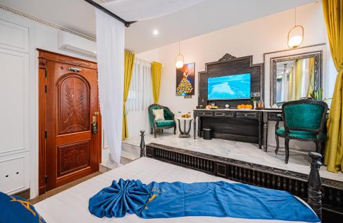 a bedroom with a bed and a tv and chairs at Athena Hotel Quy Nhơn in Quy Nhon