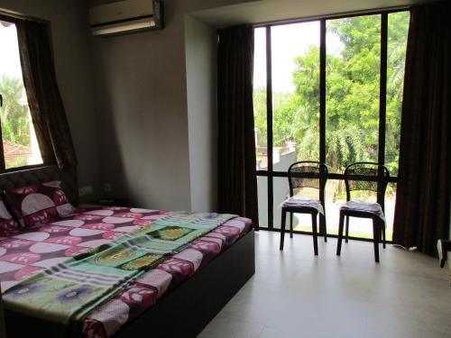 a bedroom with a bed and two chairs and a window at Ganga Kutir Oak Villa on Raichak in Raichak