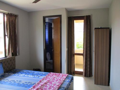 a bedroom with a bed and a door to a balcony at Ganga Kutir Oak Villa on Raichak in Raichak