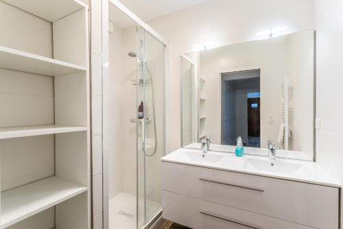 La salle de bains blanche est pourvue d'un lavabo et d'une douche. dans l'établissement Ty Granny - Superbe vue sur le port, à Saint-Cast-le-Guildo
