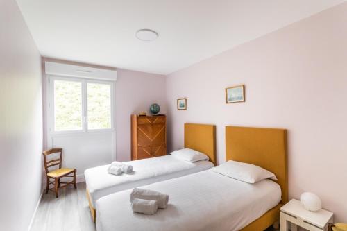 a bedroom with two beds and a chair and a window at Ty Granny - Superbe vue sur le port in Saint-Cast-le-Guildo