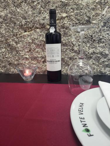 a bottle of wine and a candle on a table at Fonte Velha in Castelões- Penafiel