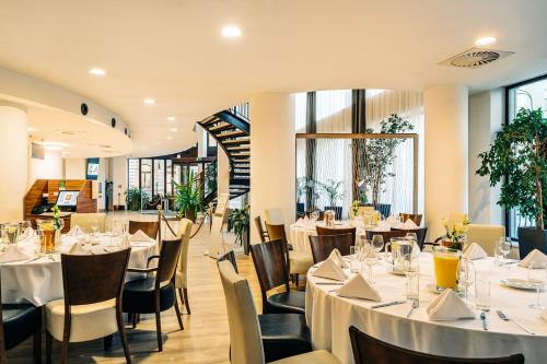 a restaurant with white tables and chairs and windows at Holiday Inn Łódź by IHG in Łódź