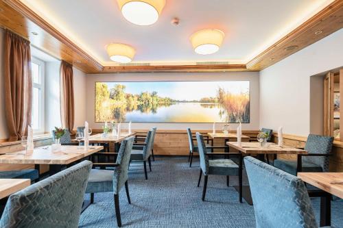 a restaurant with wooden tables and chairs and a large screen at Hotel Markgraf in Lehnin