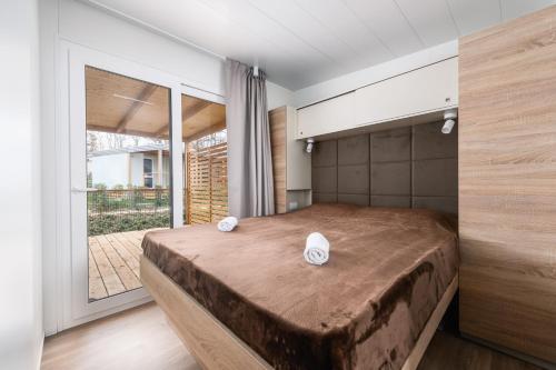 a bedroom with a large bed and a large window at Adriamar Mobile Homes in Camping Park Umag in Umag