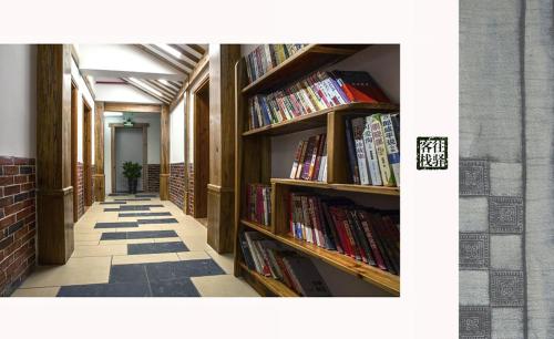 a library with wooden shelves filled with books at Zhangjiajie Wangyi Inn in Zhangjiajie