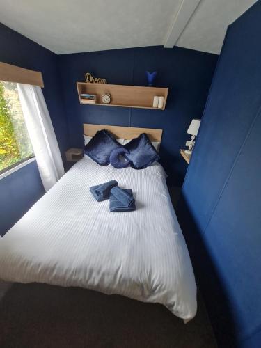 a blue bedroom with a bed with two blue pillows at Lovely caravan at Harts Holiday Park Leysdown-on-Sea in Leysdown-on-Sea