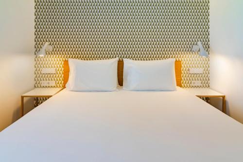 a white bed with two pillows on top of it at Tandem Torre de la Calahorra in Córdoba