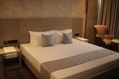 a bedroom with a bed with white sheets and pillows at MothiMahal Residency Thrissur in Trichūr