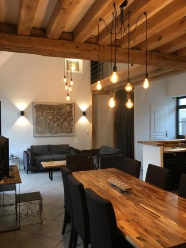 a dining room and living room with a wooden table at Les gîtes du Val de Chambord in Huisseau-sur-Cosson