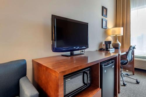a room with a desk with a tv and a chair at Comfort Inn Apalachin - Binghamton W Route 17 in Apalachin