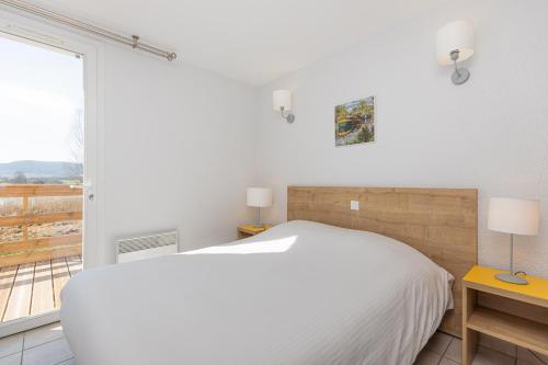 Heudicourt-sous-les-CôtesにあるHébergements du Lac de Madineのベッドと窓のある白い寝室