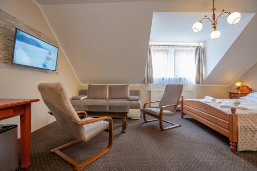 a bedroom with a bed and a couch and a chair at Hotel Diament in Szklarska Poręba