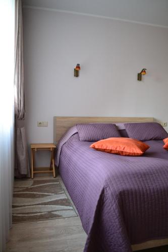 een paars bed met een rood kussen erop bij Šaulys1 in Druskininkai