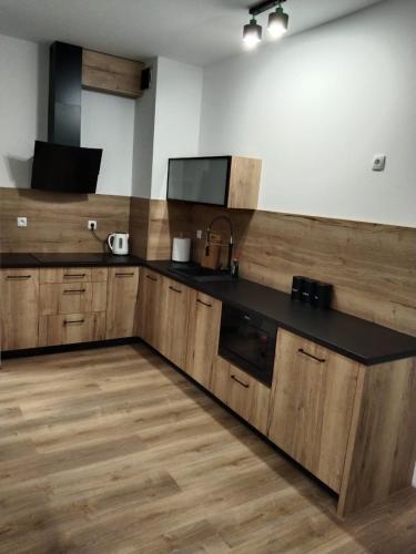 uma cozinha com armários de madeira e um balcão preto em Apartament Berylowa 1 em Konin