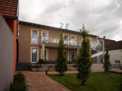 a house with a balcony and trees in the yard at Gästehaus Reßler in Harxheim