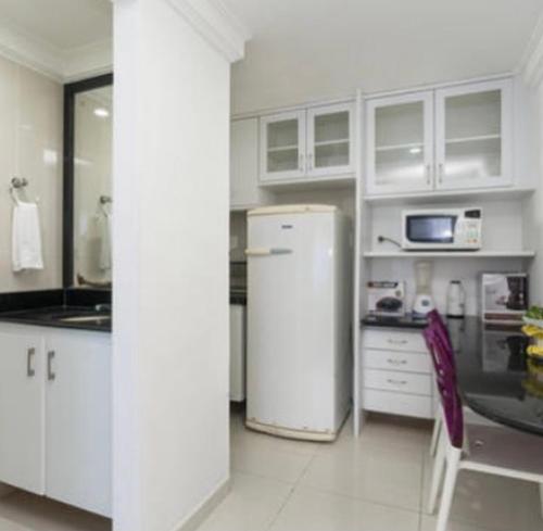 a kitchen with white cabinets and a white refrigerator at Flat em Boa Viagem in Recife