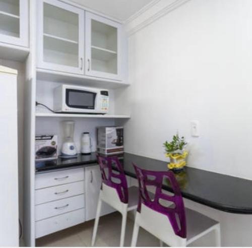 a kitchen with two purple chairs and a counter at Flat em Boa Viagem in Recife