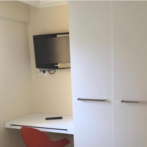a room with a tv and a desk with a red chair at Flat em Boa Viagem in Recife