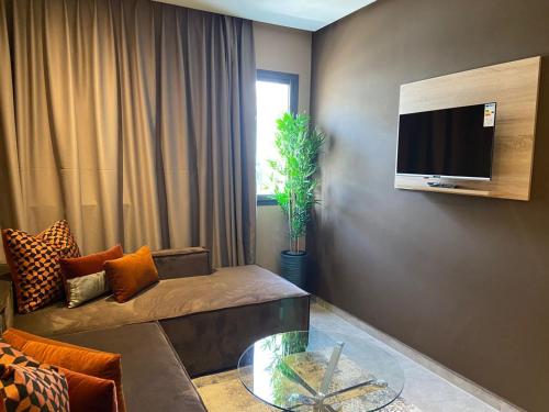 a living room with a couch and a tv on a wall at Atlas-Résidence by Rent-Inn in Rabat