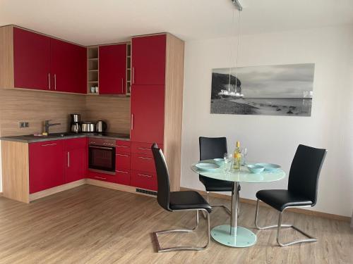 a kitchen with red cabinets and a table and chairs at Traumferienwohnung Ostseebad Baabe - Rügen in Baabe