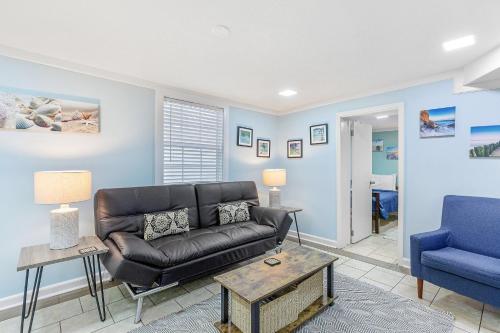 a living room with a leather couch and a blue chair at 23 Center St - Sunny Side Down - Downstairs Apartment in Folly Beach