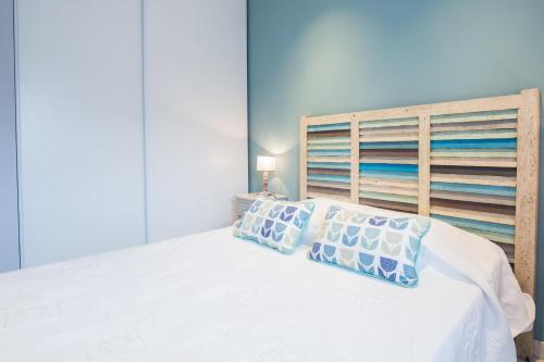 Schlafzimmer mit einem weißen Bett mit einem Kopfteil aus Holz in der Unterkunft U Fornu in Patrimonio