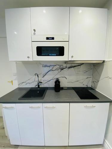 une cuisine blanche avec un évier et un micro-ondes dans l'établissement Le petit écrin de Deauville, à Deauville