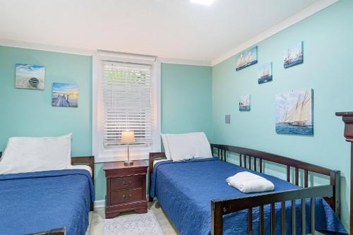 Duas camas num quarto com paredes azuis e uma janela. em 23 Center St - Sunny Side Down - Downstairs Apartment em Folly Beach