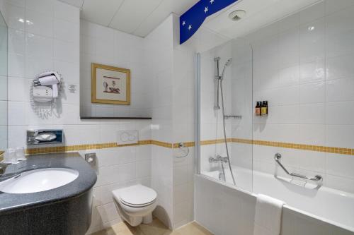 a bathroom with a toilet, sink, and shower at Grand Magic Hotel Marne La Vallée - ex Magic Circus in Magny-le-Hongre