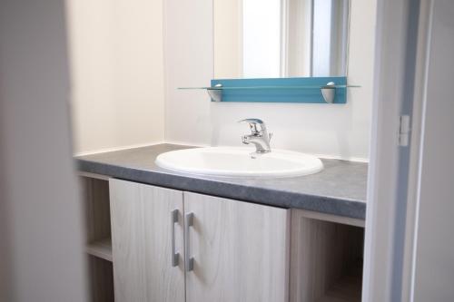 une salle de bain avec un lavabo et un miroir dans l'établissement Mobil Home XXL 4 chambres - Camping Le Domaine d'Oléron, à Foulerot